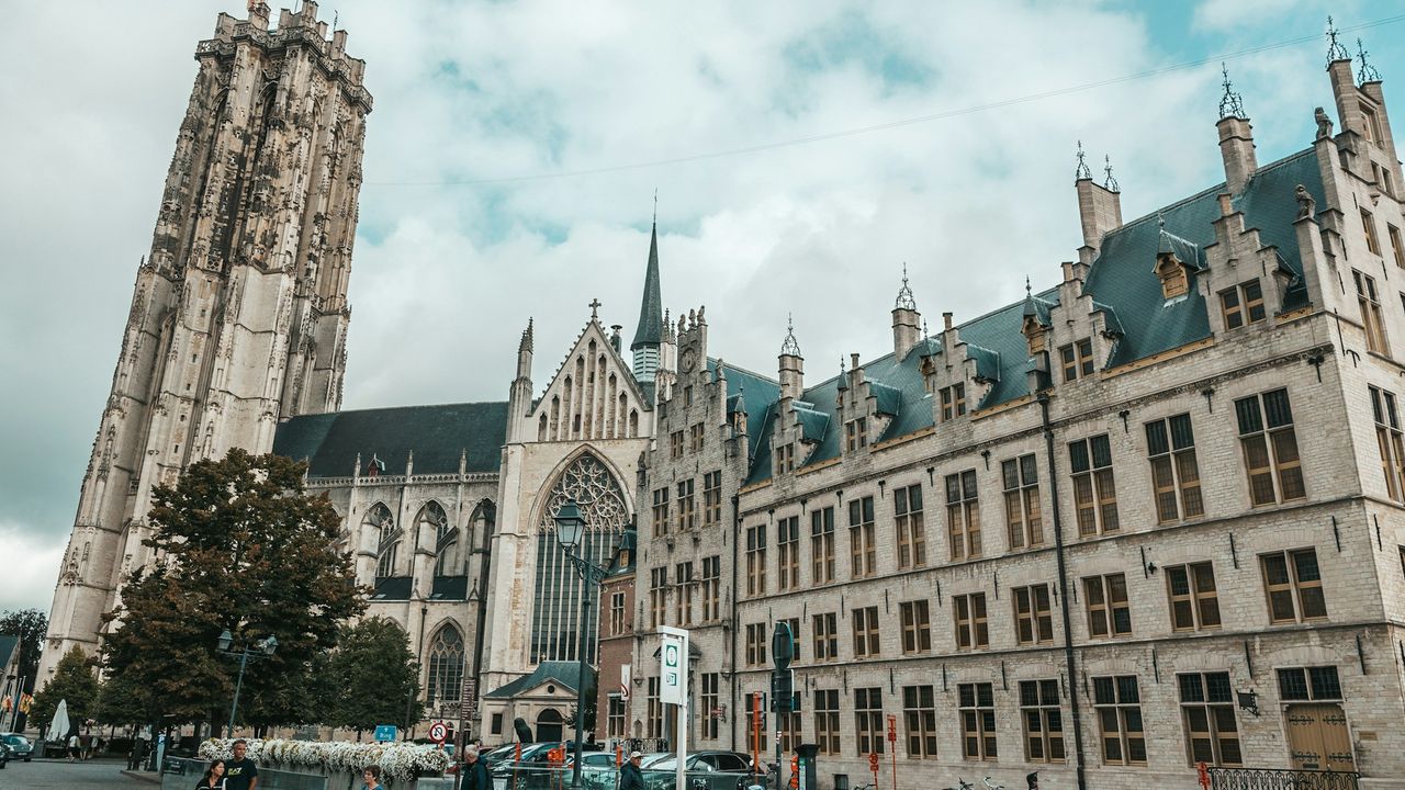 Vue sur la Grand-Place de Malines avec la cathédrale Saint-Rombaut et son imposante tour inachevée dominant les toits de la vieille ville