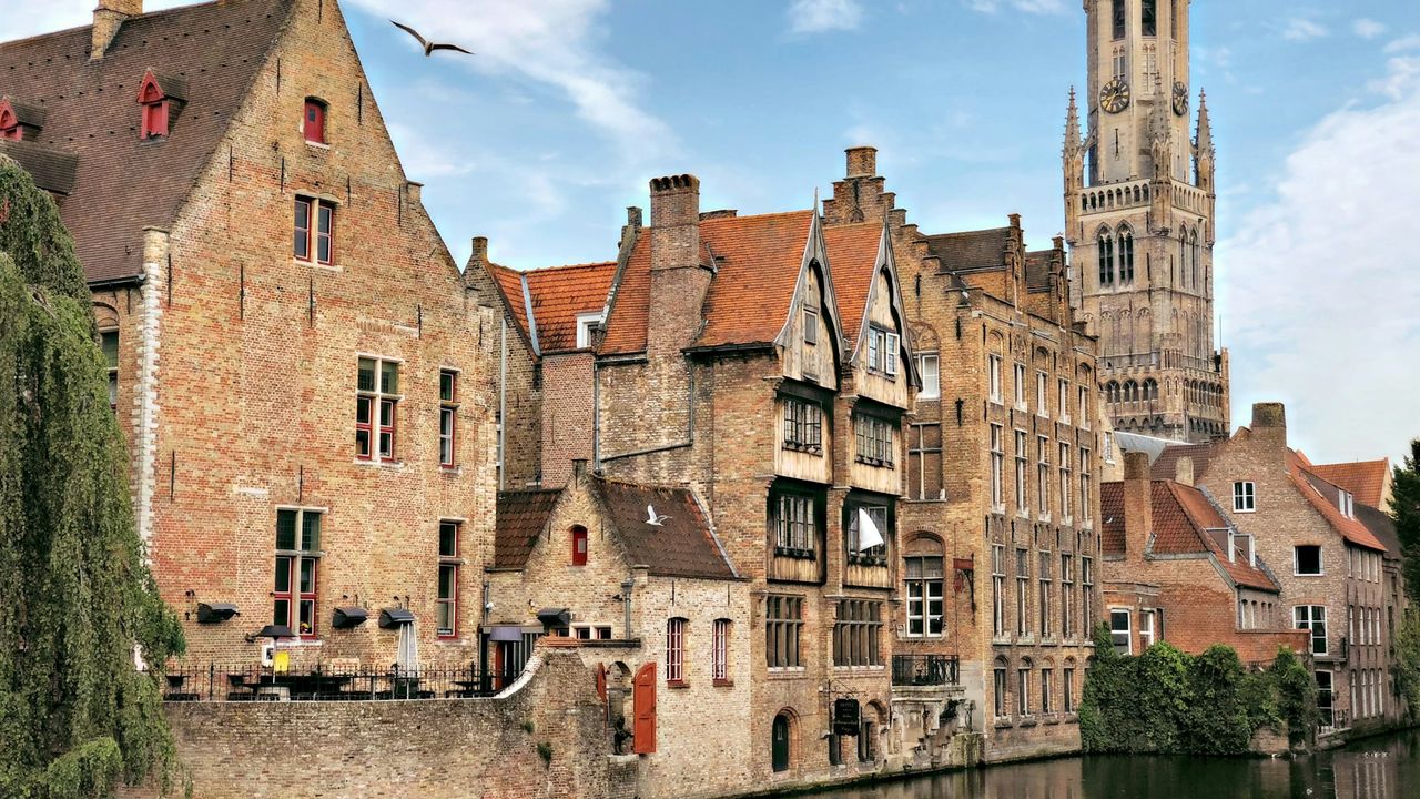 Vue sur les canaux de Bruges avec le Beffroi se dressant au-dessus des toits médiévaux