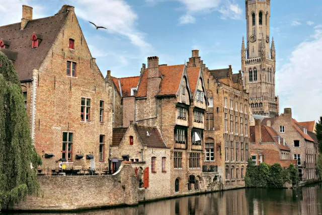 Vue sur les canaux de Bruges avec le Beffroi se dressant au-dessus des toits médiévaux