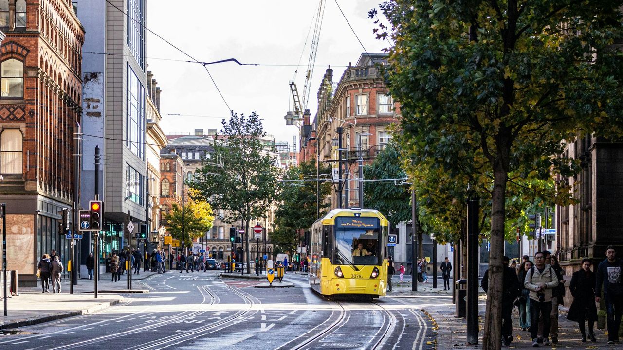 Manchester city street with a yellow tram and pedestrians